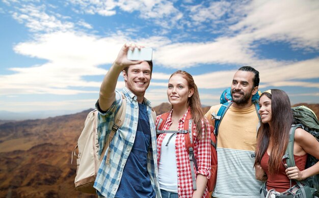 des amis avec un sac à dos prenant un selfie par smartphone