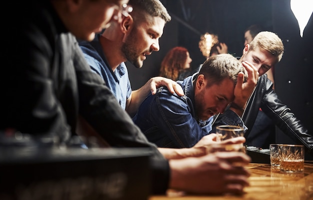 Amis se reposant dans le pub avec de l'alcool dans les mains