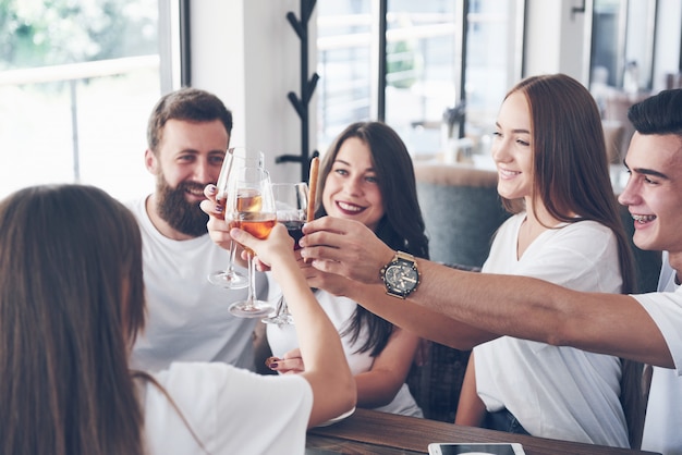 Des amis se sont réunis à table avec une cuisine délicieuse avec des verres de vin rouge pour célébrer une occasion spéciale