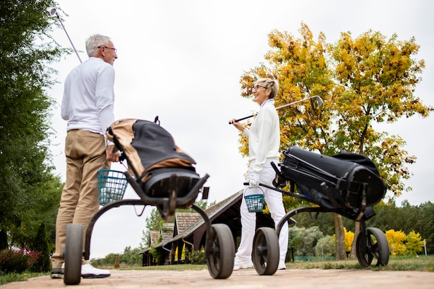 Amis seniors avec équipement de golf marchant jusqu'à la zone verte pour commencer à jouer au golf.