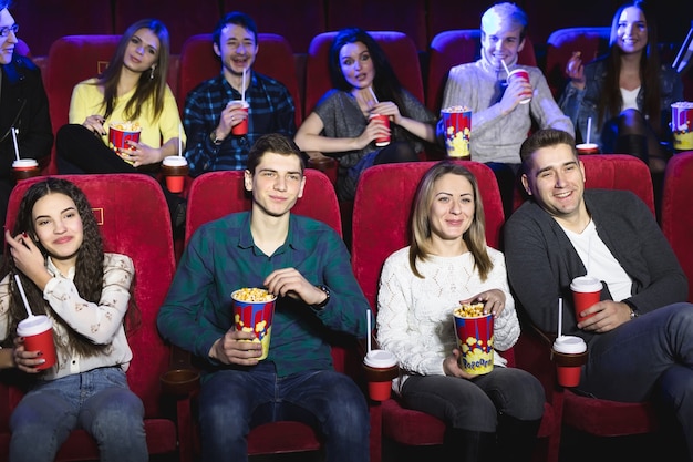 Des amis sont assis dans un cinéma regarder un film en train de manger du pop-corn