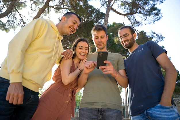 Amis souriant, ils regardent le même téléphone portable