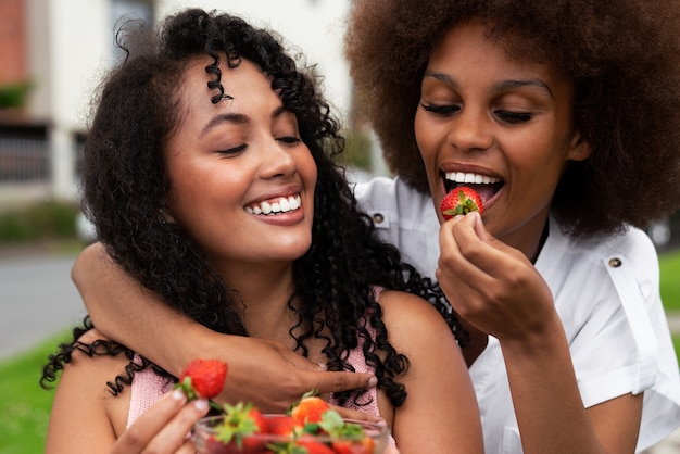 Photo amis souriants à coup moyen mangeant des fraises