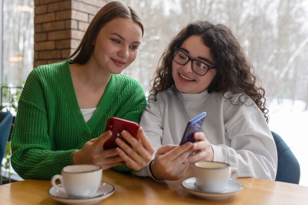 Amis souriants de plan moyen avec smartphone