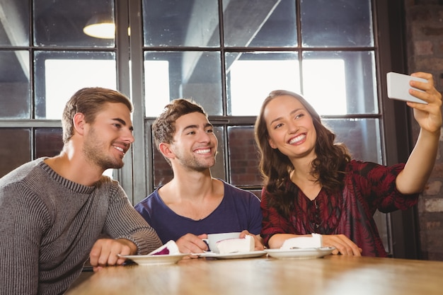 Amis souriants prenant un café et prenant des selfies