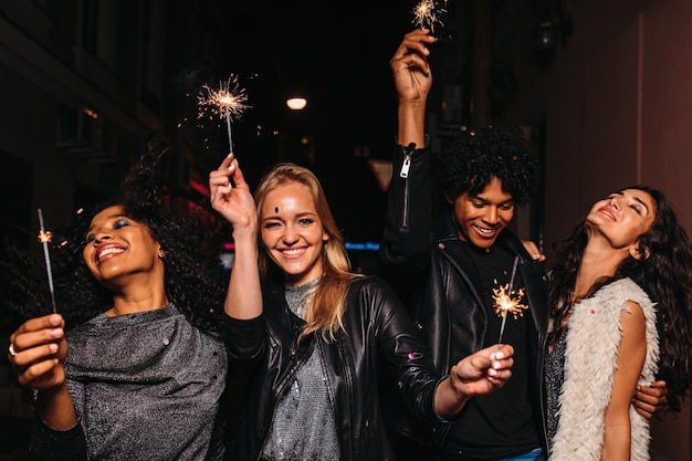 Des amis souriants tenant des étincelles allumées à la fête