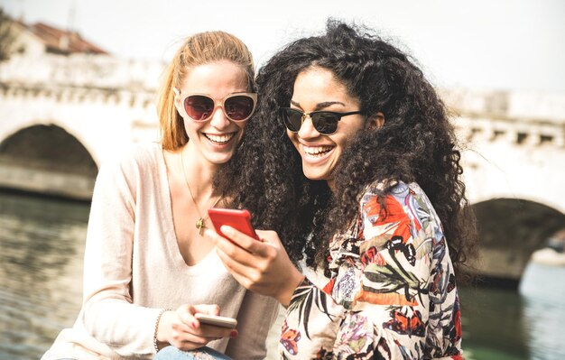 Des amis souriants en utilisant leur smartphone.