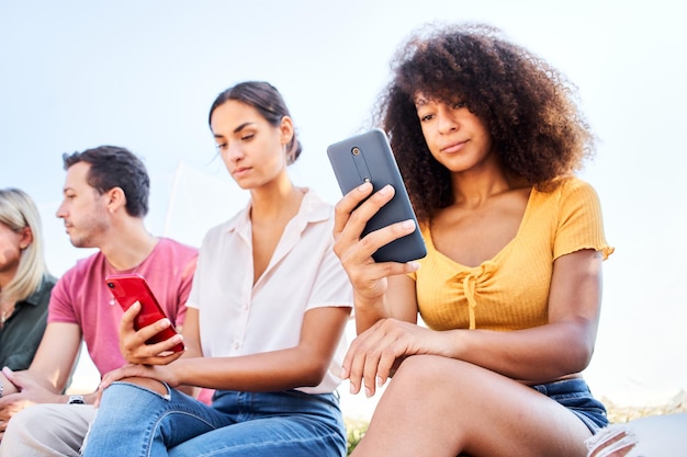 Amis utilisant la dépendance au téléphone, les médias sociaux et la technologie, des jeunes fous et des filles, un groupe malheureux