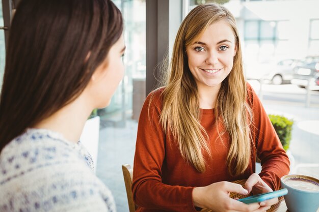 Amis utilisant un smartphone et prenant un café dans un café