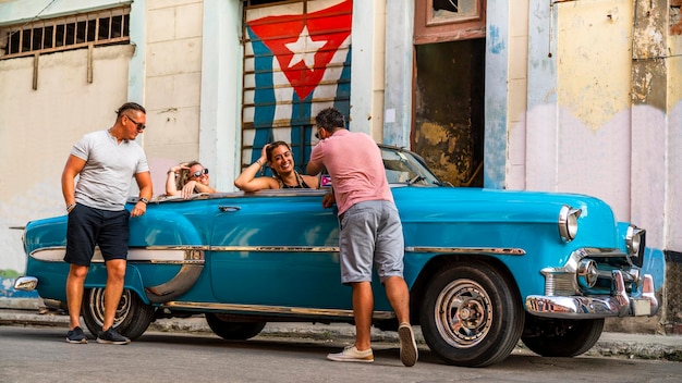 Des amis avec une voiture vintage dans la rue.