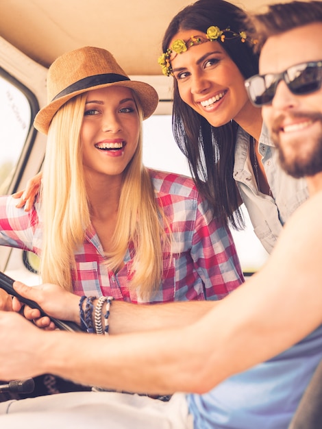 Amis en voyage sur la route. Trois jeunes joyeux regardant la caméra et souriant alors qu'ils étaient assis à l'intérieur de leur minibus