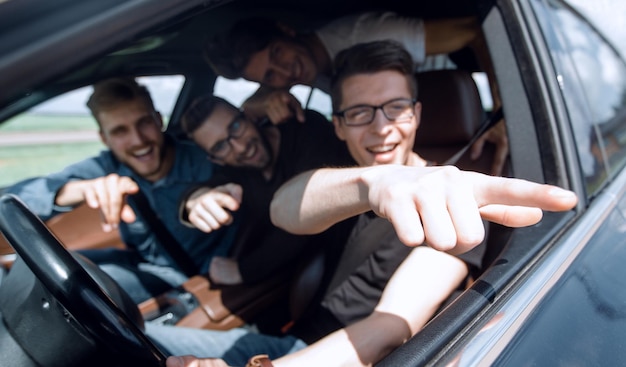 Amis de vue de côté assis dans la voiture et regardant le voyage camerajoint