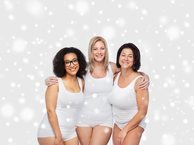 amitié, beauté, corps positif et concept de personnes - groupe de femmes heureuses de taille plus en sous-vêtements blancs sur la neige
