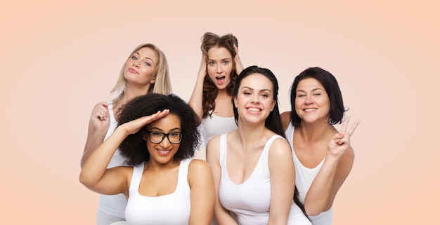 Amitié, beauté, corps positif et concept de personnes - groupe de femmes heureuses de taille plus en sous-vêtements blancs s'amusant et faisant des grimaces sur fond beige