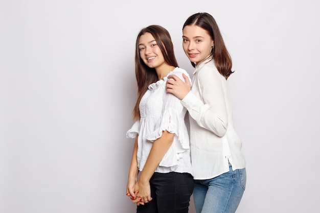 Amitié, conception de t-shirt et concept de personnes heureuses. deux filles qui rient en t-shirts blancs