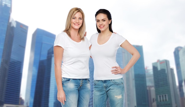 amitié, diversité, corps positif et concept de personnes - groupe de femmes différentes heureuses en t-shirts blancs étreignant