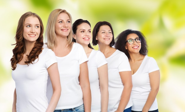 Amitié, diversité, corps positif et concept de personnes - groupe de femmes heureuses de différentes tailles en t-shirts blancs sur fond naturel vert