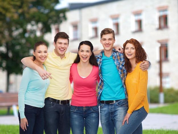 Amitié, éducation, vacances d'été et concept de personnes - groupe d'adolescents souriants debout et étreignant sur fond de campus