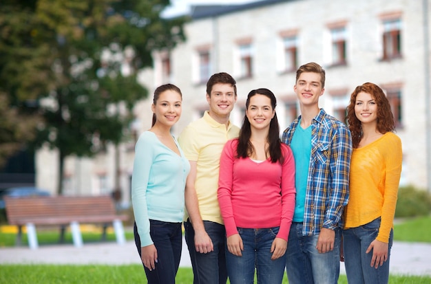 Amitié, éducation, vacances d'été et concept de personnes - groupe d'adolescents souriants debout sur fond de campus