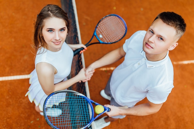 L'amitié Gagne. Deux Jolies Joueuses De Tennis Se Serrant La Main Et Souriant Tout En Se Tenant Près Du Filet De Tennis.