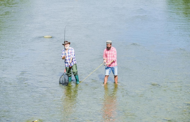 Amitié masculine Père et fils pêchant Pêcher ensemble Apprenez à l'homme à pêcher et vous le nourrirez pour la vie Week-end d'été Heureux pêcheur avec canne à pêche et filet Passe-temps et activité sportive