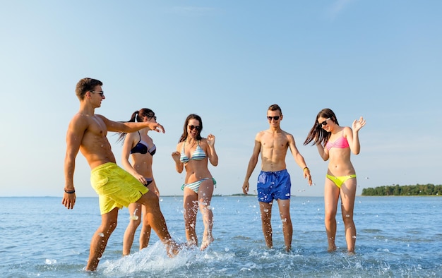 Amitié, mer, vacances d'été, vacances et concept de personnes - groupe d'amis heureux s'amusant sur la plage d'été