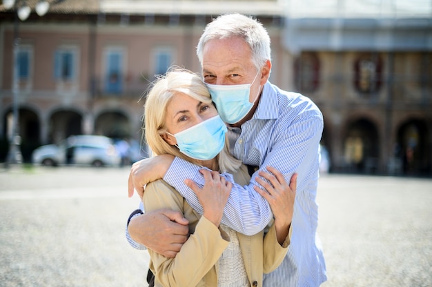 L'amour au temps des coronavirus. Couples aînés, étreindre, extérieur, porter, masques