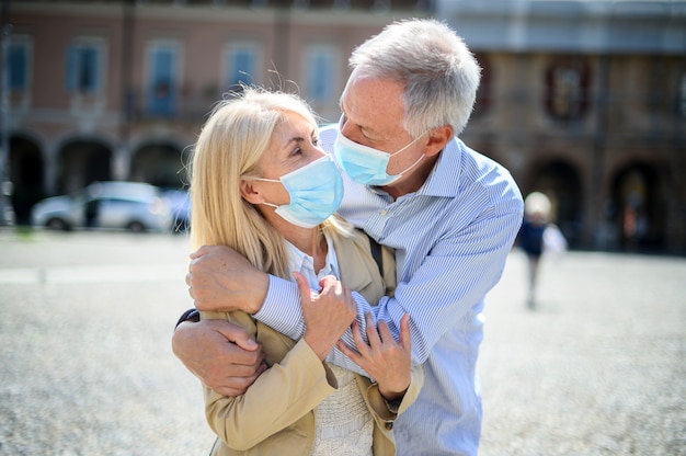 L'amour au temps du coronavirus. Couples aînés, étreindre, extérieur, porter, masques