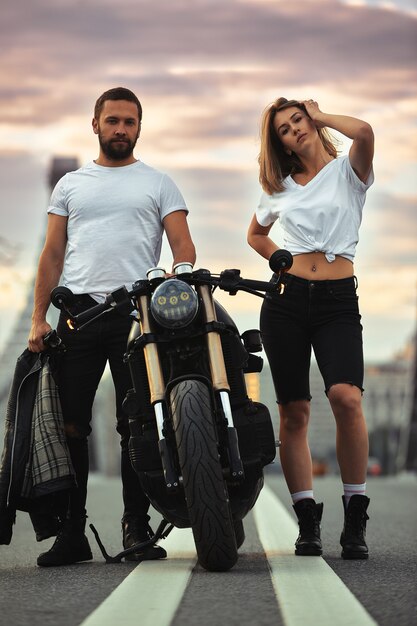 Amour et concept romantique. Beau couple à moto se dresse face à face au milieu de la route sur le pont, sur double solide.