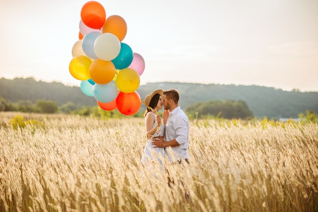 Amour couple avec des ballons câlins dans un champ de seigle