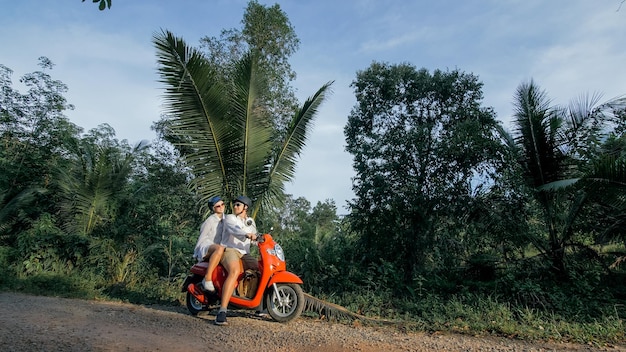 Amour couple sur moto rouge en vêtements blancs pour aller sur le sentier de la route forestière