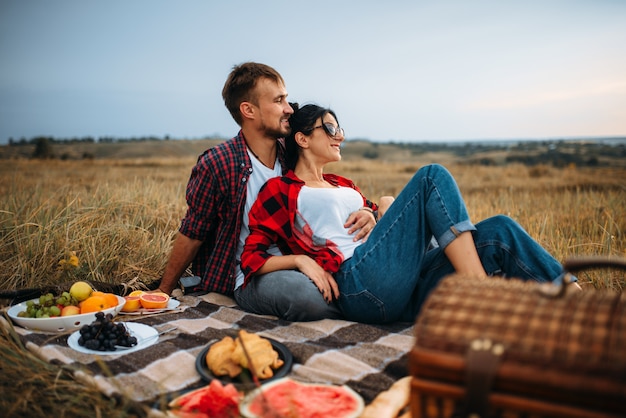 Amour couple, pique-nique sur plaid en champ d'été