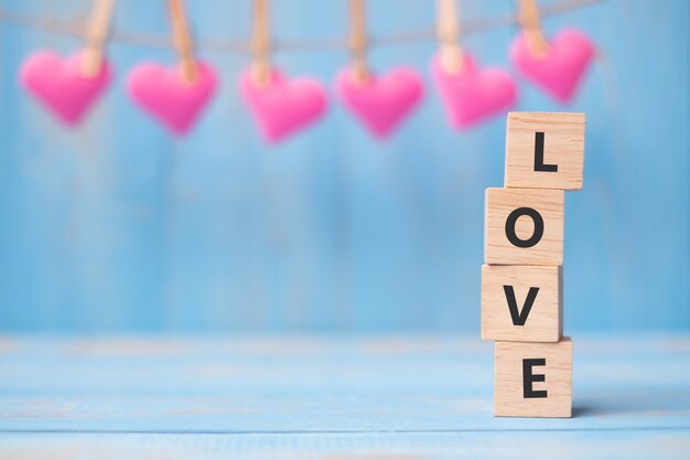 Amour cubes en bois avec décoration forme coeur rose sur fond de table bleue et copie espace pour le texte. Concept de vacances amoureuse, romantique et heureuse pour la Saint-Valentin