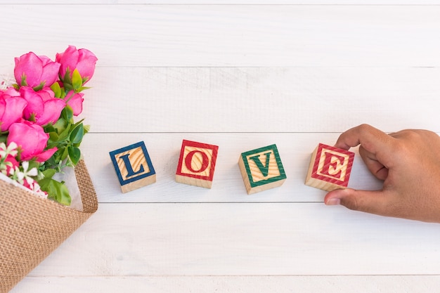 Amour écrire dans le bloc de l&#39;alphabet en bois sur une planche en bois blanc