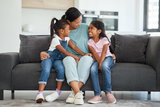 Amour familial et mère célibataire avec des enfants qui ont l'air heureux de se détendre et de sourire assis ensemble et de se lier sur un canapé dans le salon à la maison