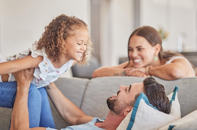 Photo amour familial et soutien de papa avec enfant jouant au jeu d'avion de levage tout en se sentant heureux sur le canapé dans leur maison costa rica souriez joie et amusement avec homme femme et fille enfant ou fille avec confiance