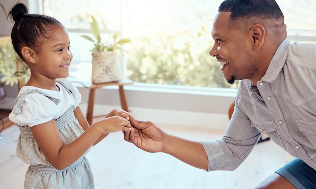 L'amour de la famille noire et le père dansent avec une fille s'amusant et se liant à la maison Sourire heureux et parent avec un enfant se tenant la main dansant et jouant aux soins et profitant de temps de qualité ensemble dans la maison