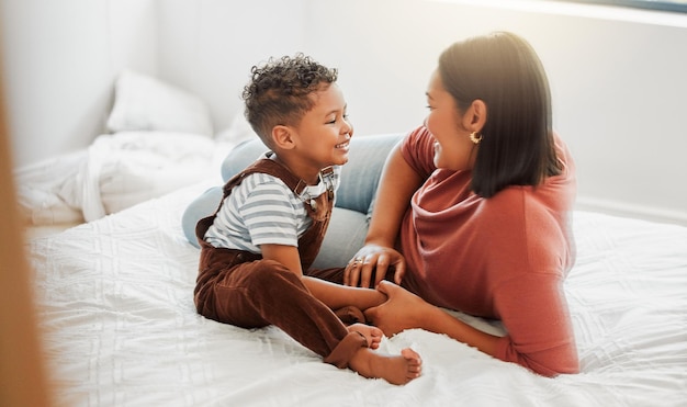 L'amour de la garde d'enfants et une mère attentionnée jouant avec son fils en bas âge dans la chambre lui apprenant à parler dans une chambre à coucher à la maison