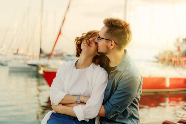 Amour joyeux couple d'amoureux assis sur un banc dans le contexte du club de yachts en mer. Romantique, concept d'histoire d'amour