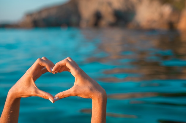 Photo l'amour de la mer. mains en forme de coeur en mer bleue