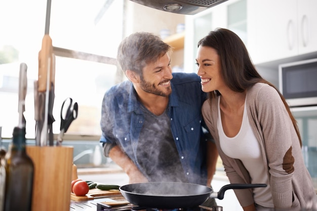 L'amour de la nourriture et un couple heureux dans la cuisine cuisinent le sourire et préparent le déjeuner dans leur maison ensemble Date du dîner et homme avec femme excité affamé et joyeux pour la préparation des repas dans leur appartement