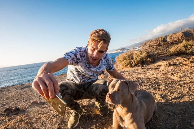 Amour pur et amitié avec un bel homme houng et un gentil chien prenant un selfie avec une activité de loisirs en plein air de téléphone intelligent technologique près de l'océan vacances et concept de couple