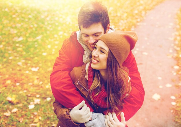 l'amour, les relations, la saison et le concept des gens - un jeune couple heureux s'embrassant dans le parc d'automne