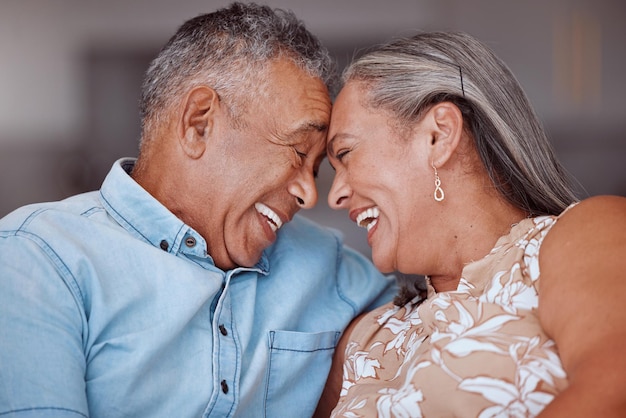 L'amour rit et un couple de personnes âgées heureux se détend et se lie dans un salon en riant et en partageant une blague amusante dans leur maison ensemble Humour familial et homme et femme âgés s'embrassent et profitent de la retraite