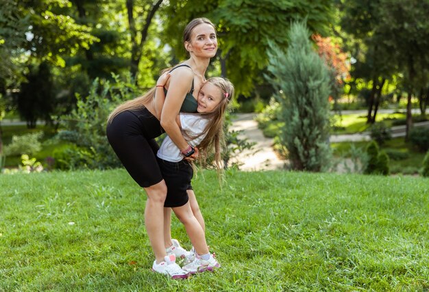 L'amour et les soins maternels Une mère en forme embrasse sa petite fille dans le parc Un mode de vie sain