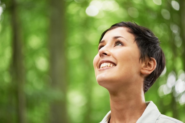 Un amour de toutes choses dans la nature Un gros plan d'une jolie jeune femme regardant vers le haut dans la canopée d'une forêt