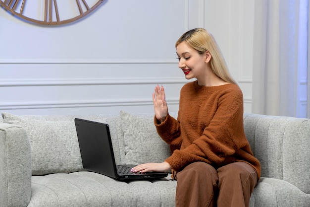 Amour virtuel jolie jeune fille blonde en pull confortable à la date de l'ordinateur à distance disant au revoir