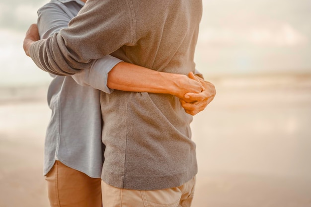 Les amoureux âgés s'embrassent et s'embrassent au coucher du soleil sur la plage Planifiez une assurance-vie avec un concept de retraite heureuse.