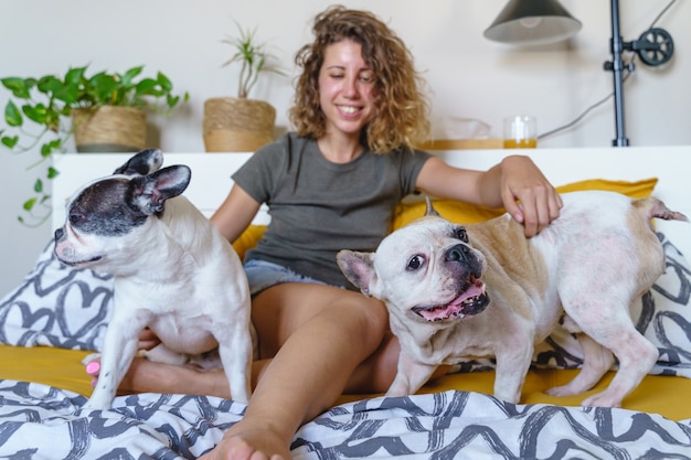 Amoureux des chiens de femme avec des bouledogues dans la chambre. Vue horizontale d'une jeune femme jouant avec un animal de compagnie à l'intérieur