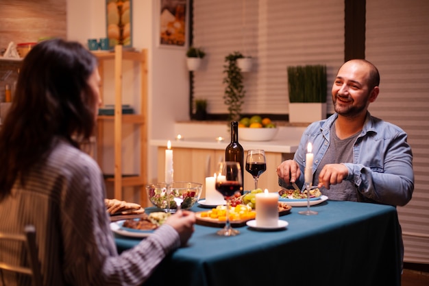 Amoureux dégustant une cuisine savoureuse tout en dînant dans la cuisine. Détendez-vous des gens heureux, assis à table dans la cuisine, savourant le repas, célébrant l'anniversaire dans la salle à manger.